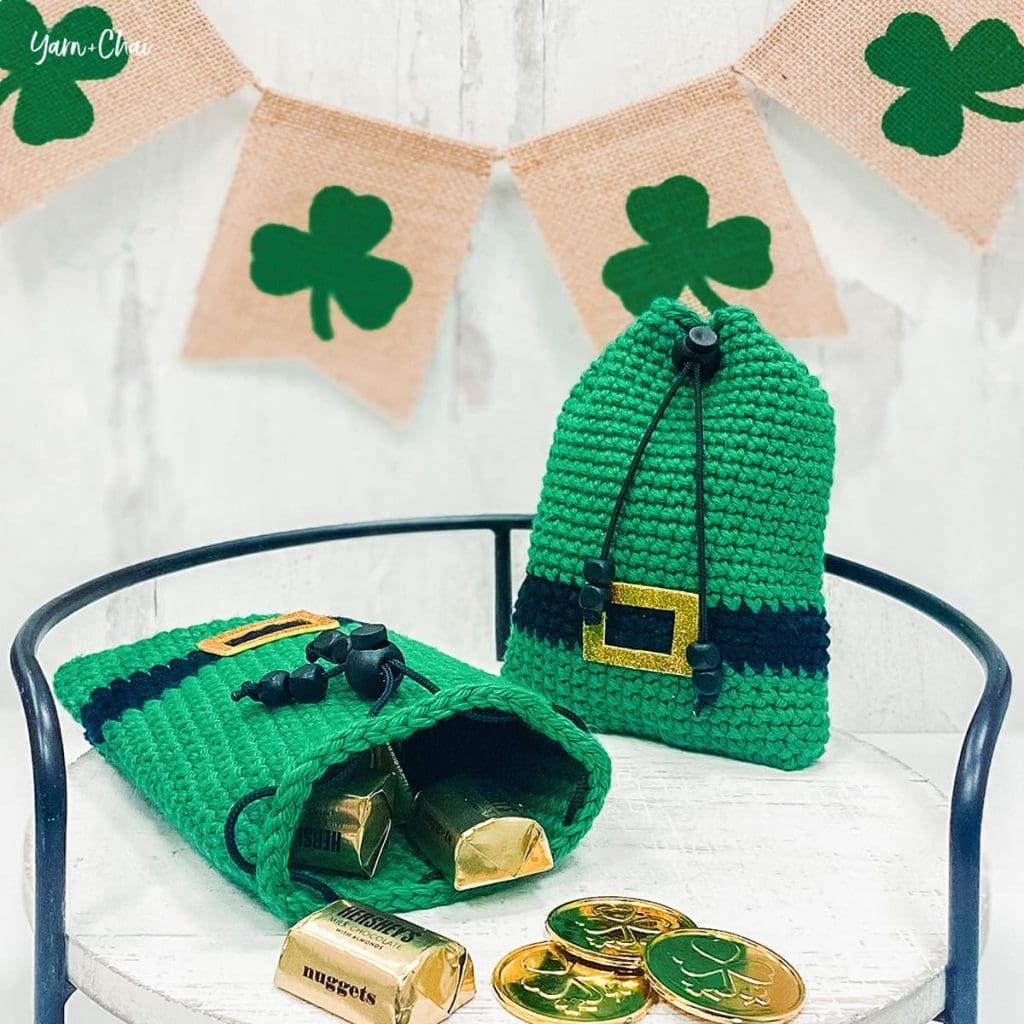 Image of green, black and gold treat bags; one is open with candy spilling out.